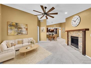 Bright living room featuring a fireplace, ceiling fan, and open floor plan to the kitchen and dining area at 8747 E Dry Creek Rd # 1623, Englewood, CO 80112