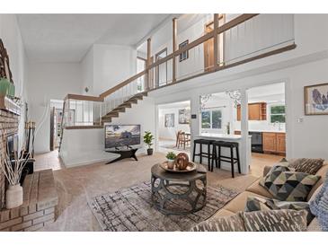 Inviting living room boasts a brick fireplace, stairs to a loft, and seamless flow to kitchen and dining area at 7507 Braun St, Arvada, CO 80005