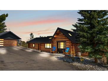 Charming log home with a black roof and two inviting blue chairs on a paved drive way at 1651 Pine Valley Rd, Evergreen, CO 80439