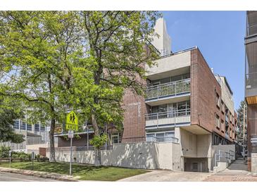Brick apartment building with a street side view, trees, and visible signage at 830 N Sherman St # 208, Denver, CO 80203