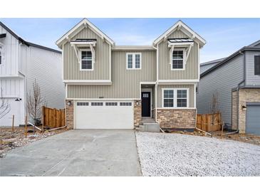 Charming two-story home featuring stone accents, gray siding, a two-car garage, and a well-manicured front yard at 16671 W 93Rd Ave, Arvada, CO 80007