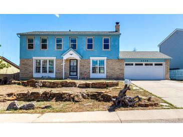 Two-story home with brick and blue siding, attached garage, and stone landscaping under a clear, blue sky at 2336 S Dawson Way, Aurora, CO 80014
