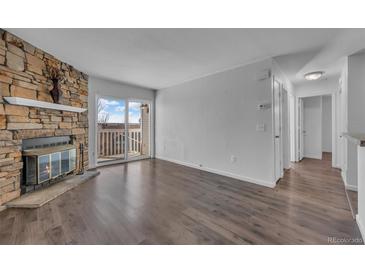 Bright living room with hardwood floors, stone fireplace, and sliding glass doors to balcony at 4460 S Pitkin St # 120, Aurora, CO 80015