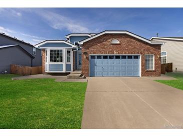 Charming two-story home with brick accents, a blue garage door, and a well-manicured front yard at 13151 Ivanhoe St, Thornton, CO 80602