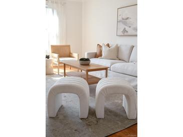 Bright living room featuring neutral tones, stylish white sofa, textured stools and modern accents at 2301 E Fremont Ave # W03, Centennial, CO 80122
