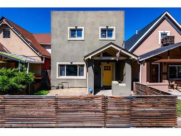 Charming two-story home featuring a bright yellow door and neat front yard landscaping at 433 Fox St, Denver, CO 80204