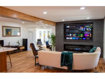 Bright living room featuring hardwood floors, modern fireplace, and a large screen tv at 8950 W 26Th, Lakewood, CO 80215
