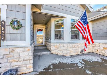 Charming front porch with stone accents, American flag, and festive wreath at 7633 S Addison Way, Aurora, CO 80016