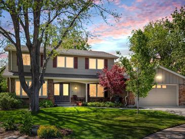 Charming two-story home with a well-manicured lawn, mature trees, and red shutters at dusk at 4175 S Sidney Ct, Denver, CO 80237