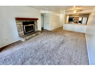 Inviting living room featuring a stone fireplace and seamless flow into the adjacent kitchen at 16001 E Alaska Pl # 7, Aurora, CO 80017