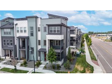 Modern townhome showcases multi-tone color scheme, landscaping, and inviting red door at 6799 Navajo St, Denver, CO 80221