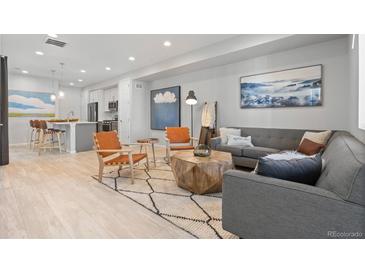 Bright living room with hardwood floors, stylish furniture, and a view into the kitchen at 12273 Karls Ln, Northglenn, CO 80241