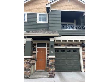Two-story home showing the front door, garage, and a second-story balcony with olive green and tan exterior colors at 7140 Simms St # 202, Arvada, CO 80004