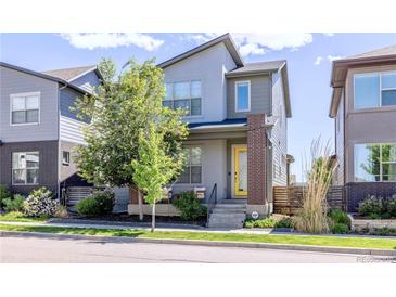Contemporary two-story home featuring gray siding, brick accents, a yellow front door and a landscaped yard at 6682 Osage St, Denver, CO 80221