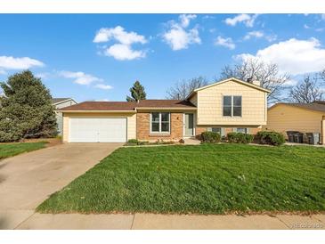 Inviting home with a well-manicured lawn, attached garage, and a mix of brick and vinyl siding at 814 Glenwood Dr, Lafayette, CO 80026
