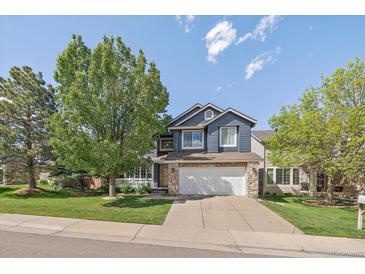Charming two-story home with blue siding, stone accents, mature landscaping, and a well-manicured front lawn at 10610 Winterflower Way, Parker, CO 80134