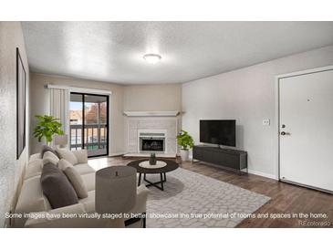 Bright living room featuring a cozy fireplace, modern furnishings, and access to a private balcony at 8335 Fairmount Dr # 9-206, Denver, CO 80247