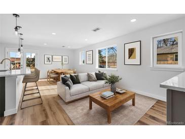 Bright living room with hardwood floors, white walls, modern furniture, and large windows providing natural light at 127 Emerald St, Broomfield, CO 80020