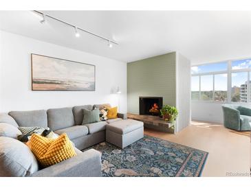 Bright living room features a charming fireplace, comfortable gray sectional and stylish decor at 1313 N Williams St # 1003, Denver, CO 80218