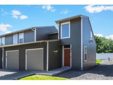 Modern townhome featuring gray siding, an attached garage, and a well-maintained lawn on a sunny day at 5415 W 16Th Ave, Lakewood, CO 80214