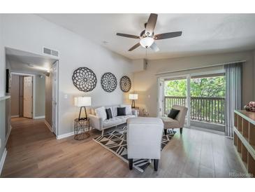 Bright living room with hardwood floors, a ceiling fan, and a sliding glass door to the balcony at 9911 E Idaho Cir # 202, Denver, CO 80247