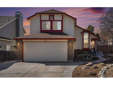 Charming two-story home boasts an attached garage, red trim, and well-manicured landscaping at 19962 E Kent Dr, Aurora, CO 80013