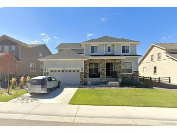Charming two-story home with stone accents, a well-manicured lawn, and an attached two-car garage at 14221 Ivanhoe St, Thornton, CO 80602