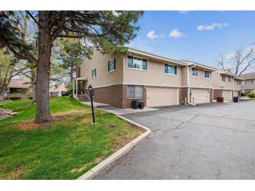 Charming townhome featuring a brick facade and attached garage with a well-maintained lawn and mature tree at 6917 E Girard Ave, Denver, CO 80224