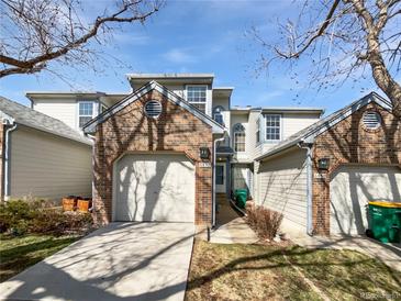 Inviting townhouse with brick accents, attached garage, and well-maintained landscaping under a bright blue sky at 6852 S Dover Way, Littleton, CO 80128