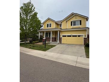 Charming yellow two-story home featuring a spacious driveway and well-manicured lawn at 4970 Laurelglen Ln, Highlands Ranch, CO 80130