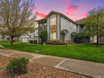 Attractive two-story condo boasts a charming stone and siding exterior with balcony, set against a green lawn and trees at 3262 E 103Rd Dr # 1806, Thornton, CO 80229