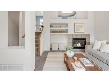 Cozy living room with a fireplace, open shelving, decor, and staircase access in a bright, airy interior at 9369 Longs Peak Dr, Commerce City, CO 80640