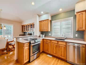 Well-equipped kitchen with stainless steel appliances, wooden cabinets, and granite countertops at 13990 E Chenango Dr, Aurora, CO 80015