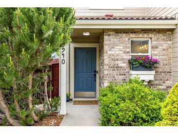 Charming home entrance featuring a blue front door, brick facade, and well-manicured greenery at 3940 Malaya St, Denver, CO 80249