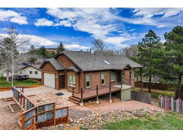 Charming raised two-story home with brown stucco siding, gray roof, and lovely landscaping at 459 Virginia Ave, Palmer Lake, CO 80133