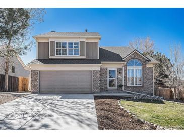 Charming two-story home featuring a brick facade, manicured lawn, and attached two-car garage at 5821 S Quatar Cir, Centennial, CO 80015