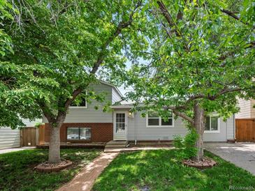 Charming home featuring a brick and siding exterior and mature trees along the front yard and brick walkway at 4858 S Quintero Cir, Aurora, CO 80015