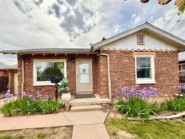 Charming brick home featuring a landscaped front yard with purple irises and a cozy front entrance at 1965 Havana St, Aurora, CO 80010