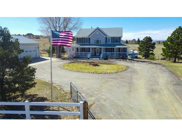 Charming two-story home with a circular driveway, lush lawn and inviting wrap-around porch at 2257 Deerpath Rd, Franktown, CO 80116