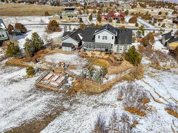 Aerial view of a large home with a landscaped yard, patio, and snow-covered surroundings at 7186 Weaver Cir, Castle Rock, CO 80104