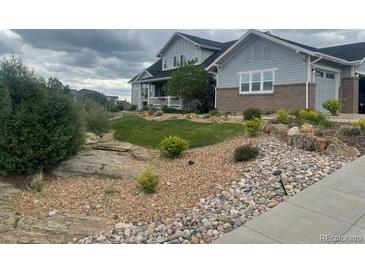 Inviting front yard with a lush green lawn, rock features, and a charming two-story home at 7186 Weaver Cir, Castle Rock, CO 80104