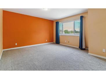 A bright bedroom with gray carpet, peach walls, and window with blue curtains at 1160 S Clinton St # 40, Denver, CO 80247