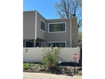 Two-story home with neutral siding, white fence, and stone chimney detail at 1160 S Clinton St # 40, Denver, CO 80247