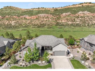 Charming single-Gathering home with stone accents and lush landscaping against a mountain backdrop at 4868 Hogback Ridge Rd, Morrison, CO 80465