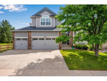 Charming two-story home with a three-car garage, manicured lawn, and mature landscaping at 11830 Snowshoe Dr, Parker, CO 80138