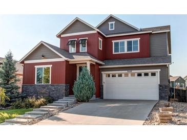 Two-story home with red and gray siding, white garage door, and landscaping at 3448 Ghost Dance Dr, Castle Rock, CO 80108