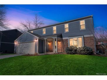 Charming two-story home with a manicured lawn, attached garage, and inviting front porch at 4643 S Vivian Ct, Morrison, CO 80465