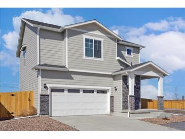 Charming two-story home featuring a two-car garage, stylish gray siding, and a welcoming covered entry at 17935 E 94Th Ave, Commerce City, CO 80022