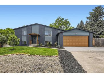 Split level home with black brick and siding, a well manicured lawn, and a two car garage at 7325 Taft Ct, Arvada, CO 80005