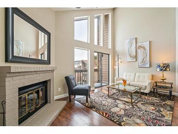 Bright living room with vaulted ceilings, fireplace, and access to a balcony at 12366 W Nevada Pl # 308, Lakewood, CO 80228